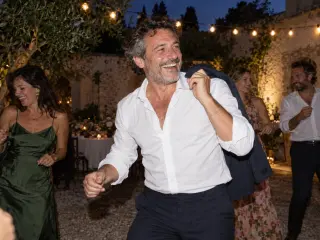 A man dancing with his jacket over his shoulder.